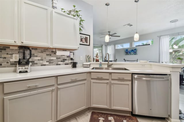 kitchen featuring pendant lighting, stainless steel dishwasher, kitchen peninsula, sink, and ceiling fan