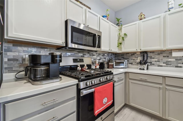 kitchen featuring appliances with stainless steel finishes, white cabinets, and decorative backsplash