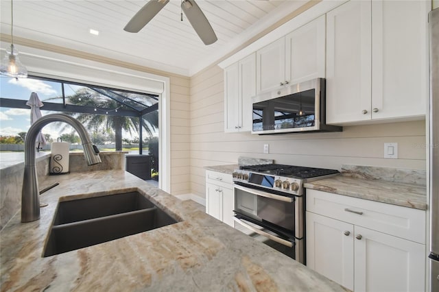 kitchen featuring light stone counters, white cabinets, hanging light fixtures, sink, and stainless steel appliances