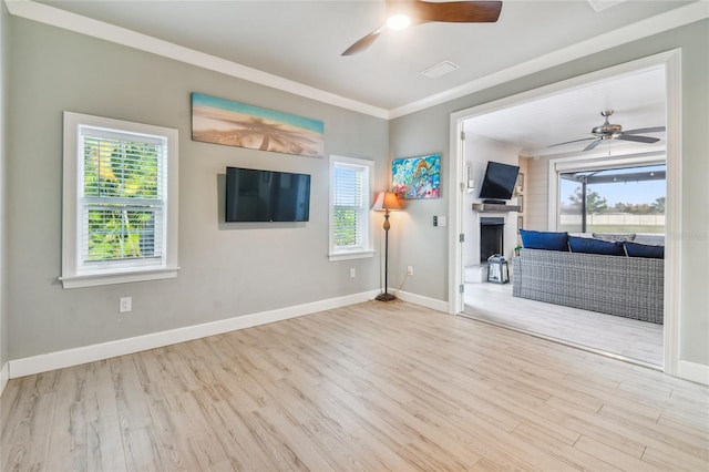 spare room featuring light wood-type flooring, ceiling fan, plenty of natural light, and crown molding