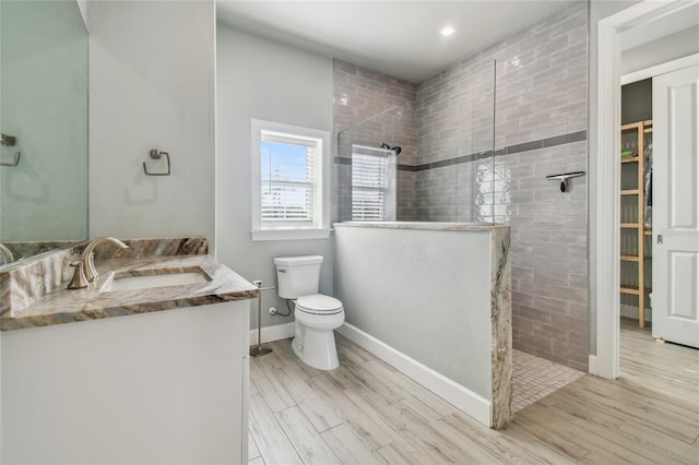 bathroom with vanity, a tile shower, toilet, and hardwood / wood-style flooring