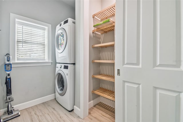 clothes washing area featuring light hardwood / wood-style flooring and stacked washer and dryer