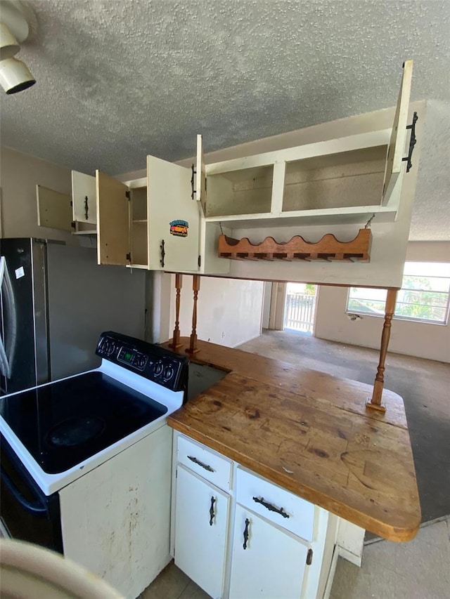 kitchen with white cabinets, white range with electric stovetop, a textured ceiling, and a healthy amount of sunlight