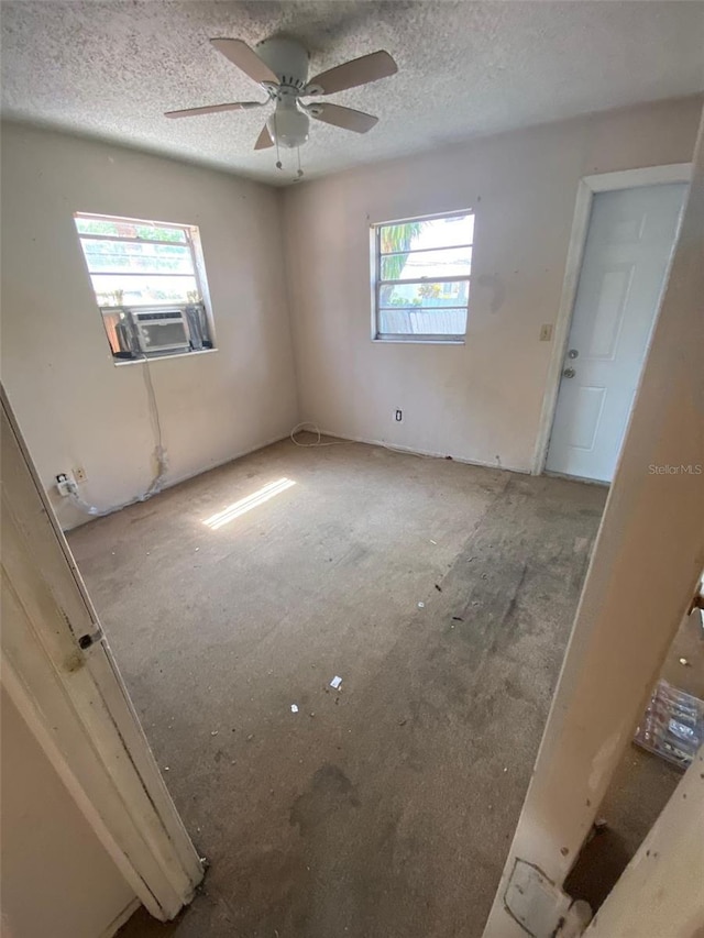 unfurnished bedroom featuring cooling unit, multiple windows, ceiling fan, and a textured ceiling