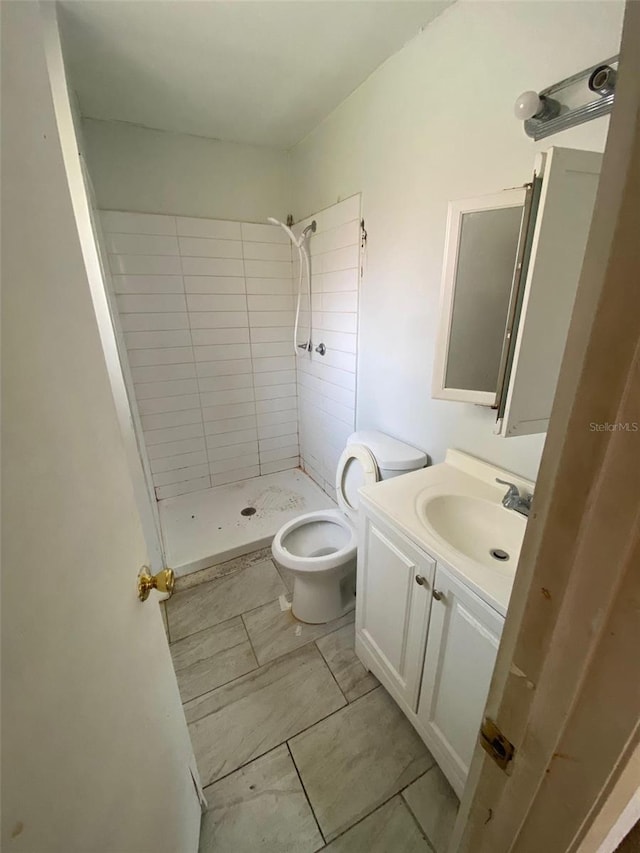 bathroom with tiled shower, toilet, and vanity