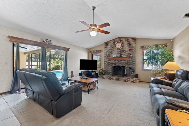 living room featuring ceiling fan, a wealth of natural light, a textured ceiling, and a brick fireplace