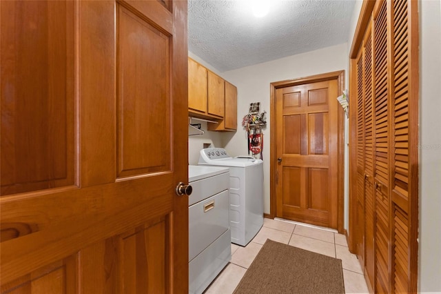 washroom with a textured ceiling, independent washer and dryer, cabinets, and light tile patterned flooring