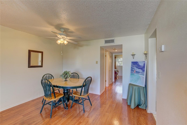 dining space featuring light hardwood / wood-style flooring, a textured ceiling, and ceiling fan