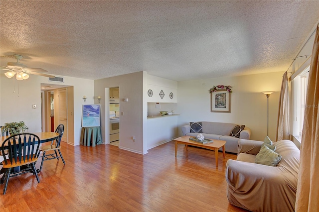 living room featuring light hardwood / wood-style flooring, a textured ceiling, and ceiling fan