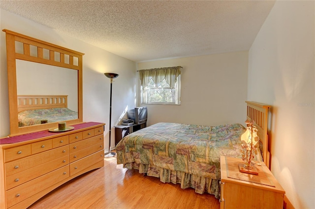 bedroom with a textured ceiling and light hardwood / wood-style floors