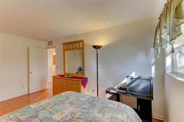 bedroom with a textured ceiling and light wood-type flooring