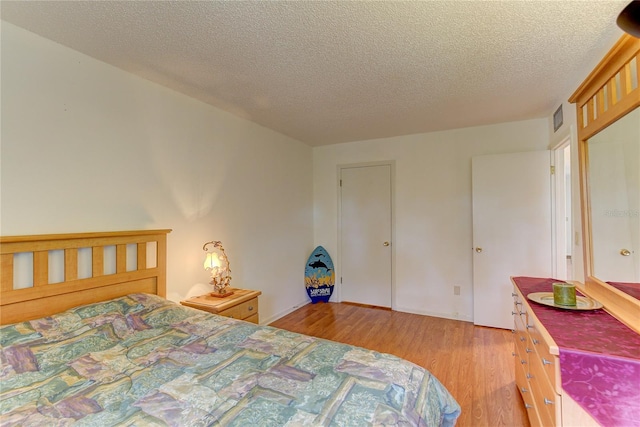 bedroom featuring light hardwood / wood-style floors and a textured ceiling