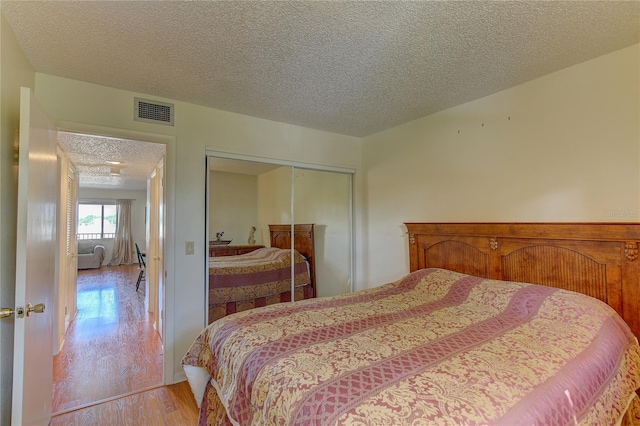 bedroom featuring a closet, a textured ceiling, and light wood-type flooring