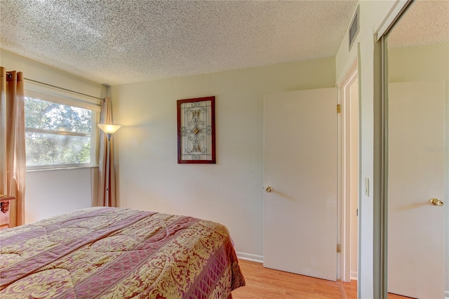 bedroom featuring a closet, light hardwood / wood-style floors, and a textured ceiling