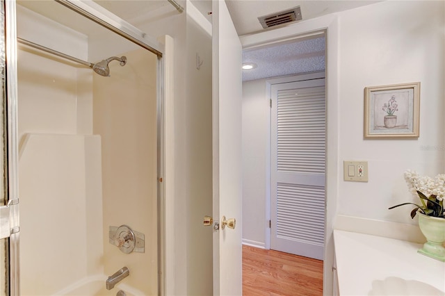 bathroom with bath / shower combo with glass door, hardwood / wood-style floors, and vanity