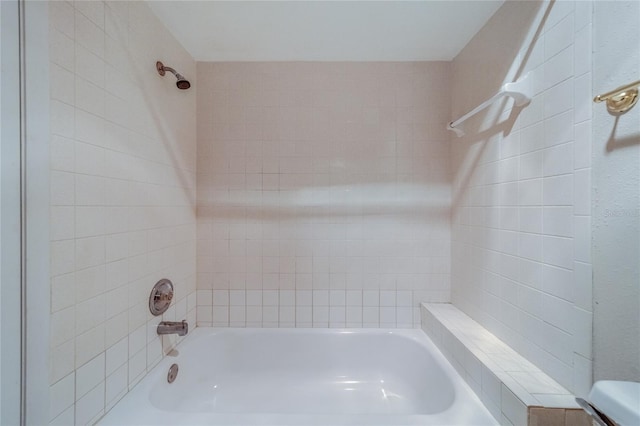 bathroom featuring toilet and tiled shower / bath combo