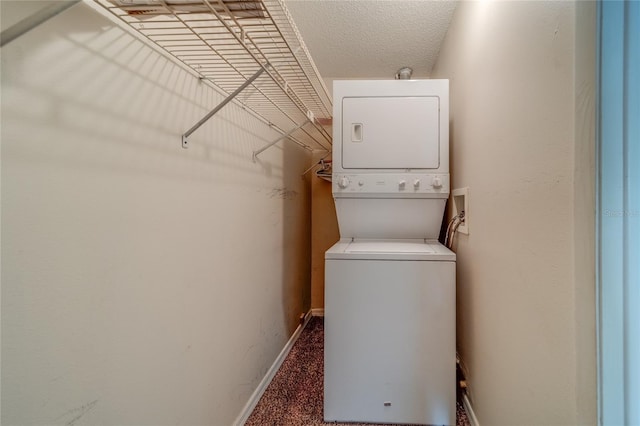 laundry room featuring a textured ceiling, dark carpet, and stacked washer / drying machine