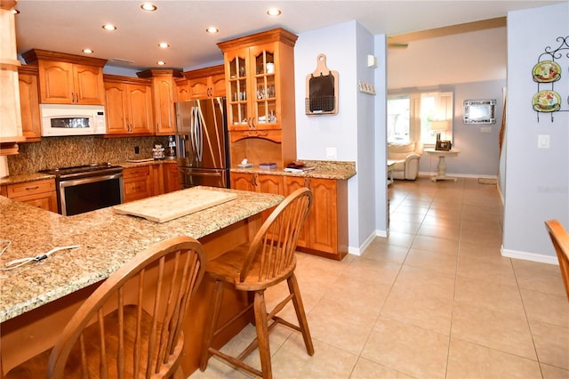 7519 Harbor View Way, Seminole, FL 33776 - kitchen with light stone countertops, stainless steel appliances, decorative backsplash, glass insert cabinets, and brown cabinets