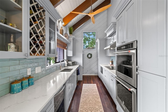 kitchen featuring dark hardwood / wood-style flooring, stainless steel double oven, sink, vaulted ceiling with beams, and hanging light fixtures