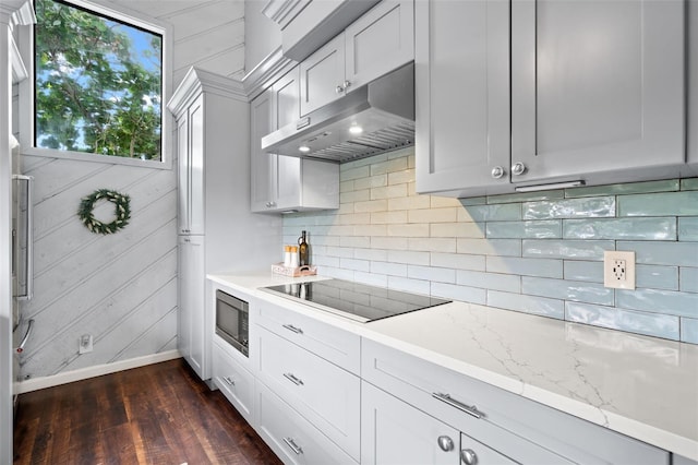 kitchen featuring white cabinets, light stone counters, black electric cooktop, and built in microwave