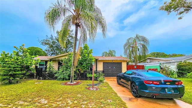 view of front of home featuring an attached garage, concrete driveway, a front yard, and fence