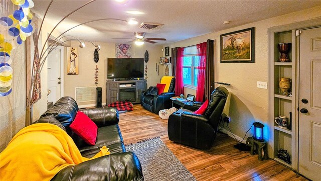 living room with a textured ceiling, hardwood / wood-style flooring, and ceiling fan