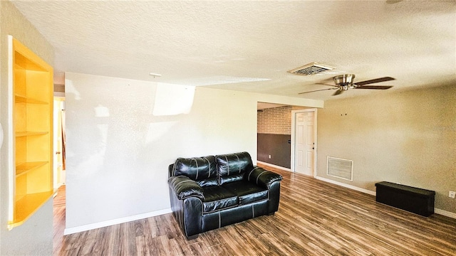 sitting room with ceiling fan, visible vents, a textured ceiling, and wood finished floors