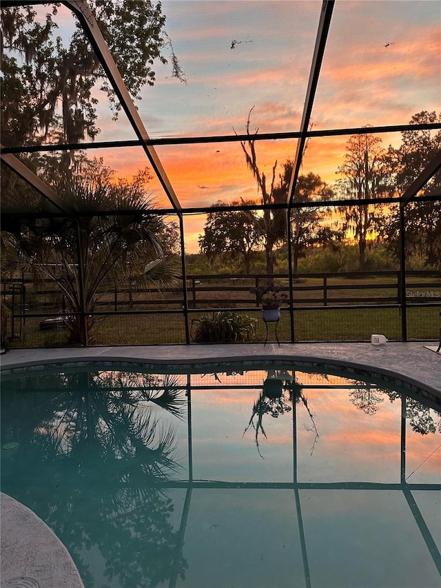 pool at dusk featuring a lanai