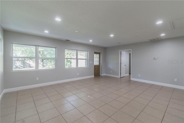 unfurnished room with a wealth of natural light, light tile patterned floors, and a textured ceiling