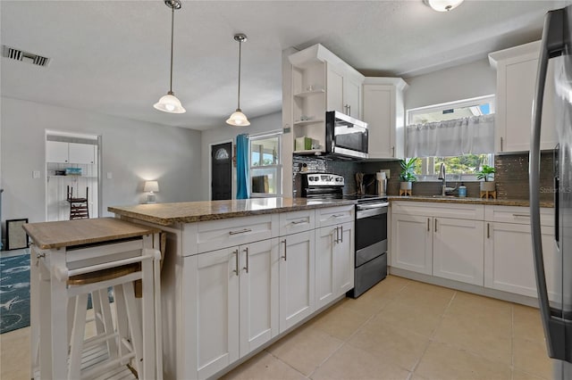 kitchen with white cabinets, stainless steel appliances, kitchen peninsula, pendant lighting, and decorative backsplash