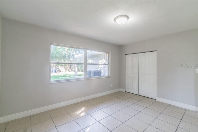 unfurnished bedroom with a textured ceiling, light tile patterned flooring, and a closet