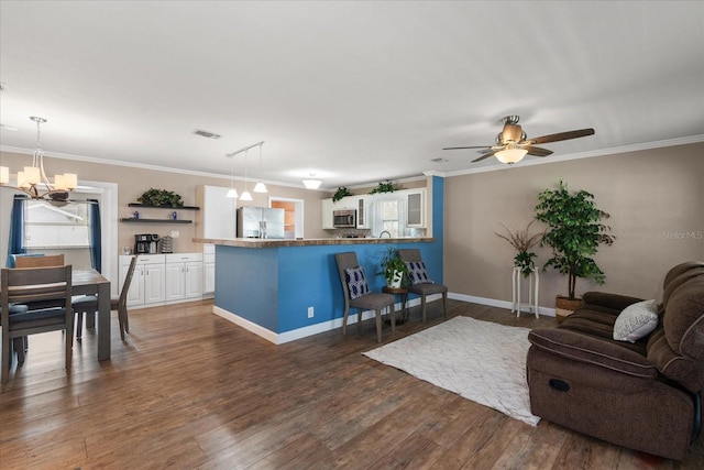 living room with dark hardwood / wood-style flooring, ceiling fan with notable chandelier, and ornamental molding