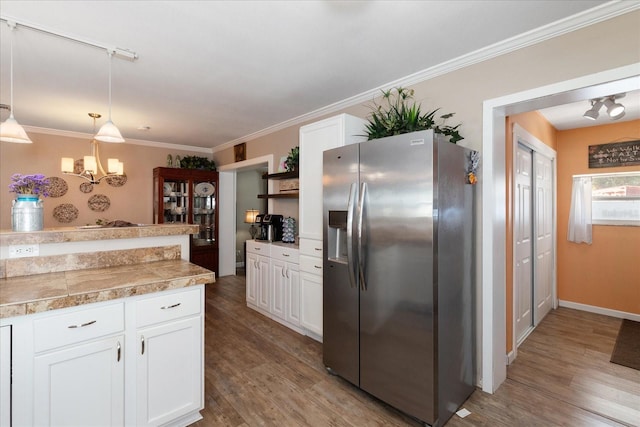 kitchen with decorative light fixtures, white cabinetry, stainless steel refrigerator with ice dispenser, and ornamental molding