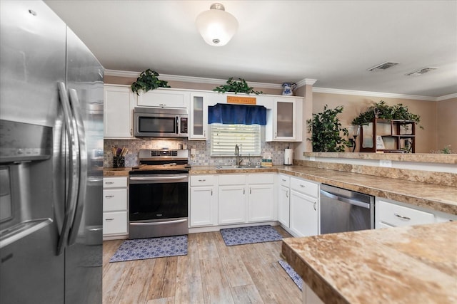 kitchen featuring sink, stainless steel appliances, backsplash, white cabinets, and light wood-type flooring