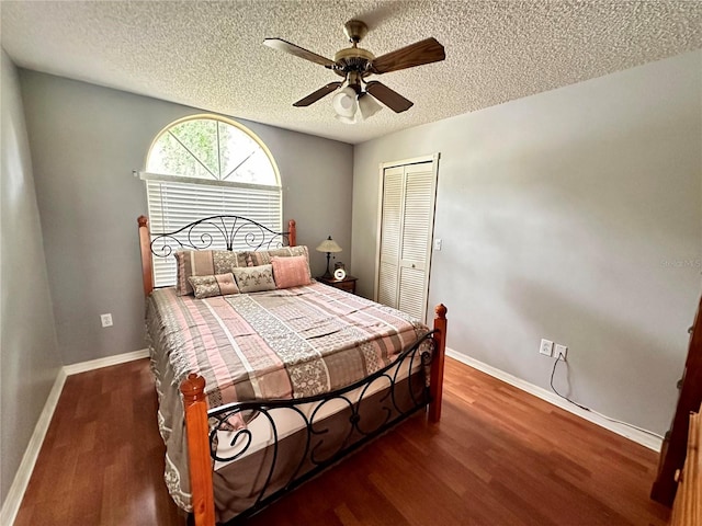 bedroom with a textured ceiling, ceiling fan, a closet, and dark hardwood / wood-style floors