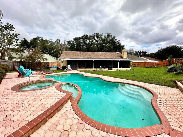 view of swimming pool with a lawn, a sunroom, an in ground hot tub, and a patio area