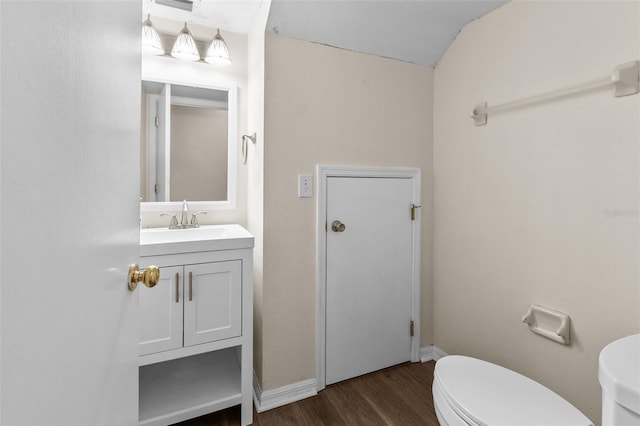 bathroom with vanity, lofted ceiling, hardwood / wood-style floors, and toilet