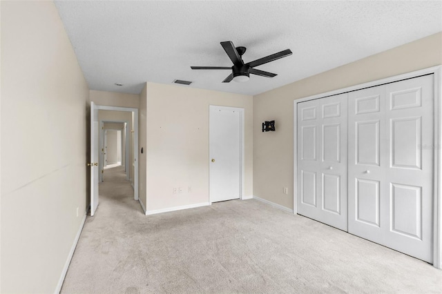 unfurnished bedroom featuring ceiling fan, light colored carpet, and a textured ceiling