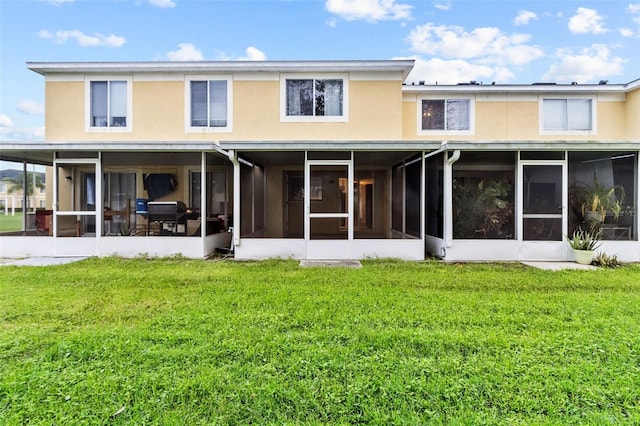 back of property featuring a sunroom and a lawn