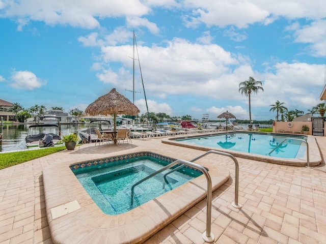 view of swimming pool featuring a hot tub, a patio, and a water view