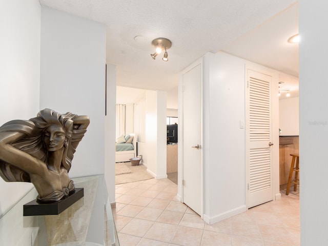 hallway featuring light tile patterned flooring and a textured ceiling