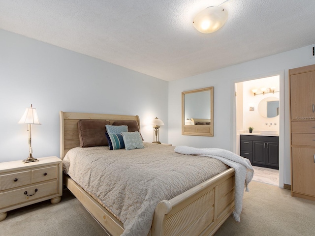 bedroom featuring light carpet, a textured ceiling, and ensuite bathroom