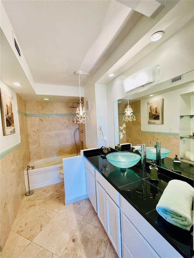 bathroom featuring a bathing tub, tile walls, a chandelier, vanity, and toilet