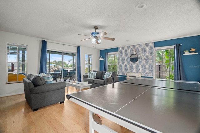 playroom with a textured ceiling, light hardwood / wood-style floors, and ceiling fan