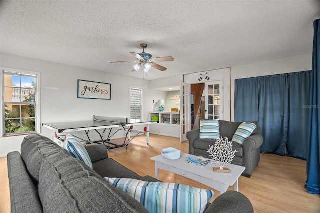 living room featuring a textured ceiling, light wood-type flooring, and ceiling fan