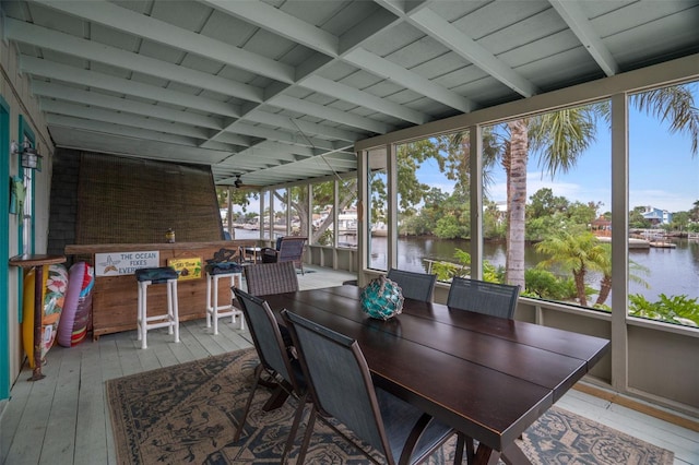 sunroom featuring beamed ceiling and a water view