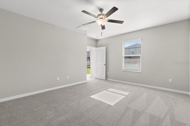 unfurnished room featuring a textured ceiling, a healthy amount of sunlight, ceiling fan, and light colored carpet