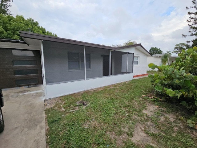 back of property with a yard and a sunroom