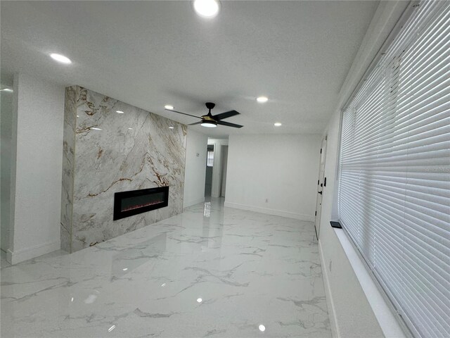 unfurnished living room with a textured ceiling, ceiling fan, and a premium fireplace