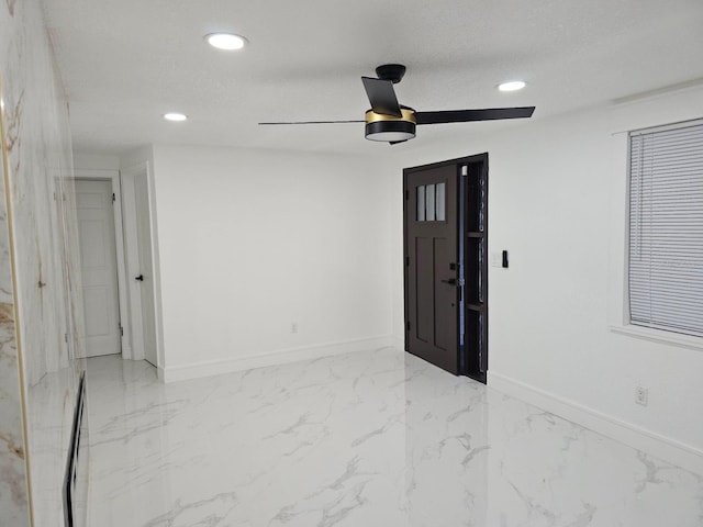 foyer entrance with ceiling fan and a textured ceiling